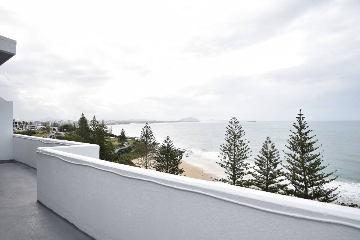 A balcony with a view of a beach and ocean.