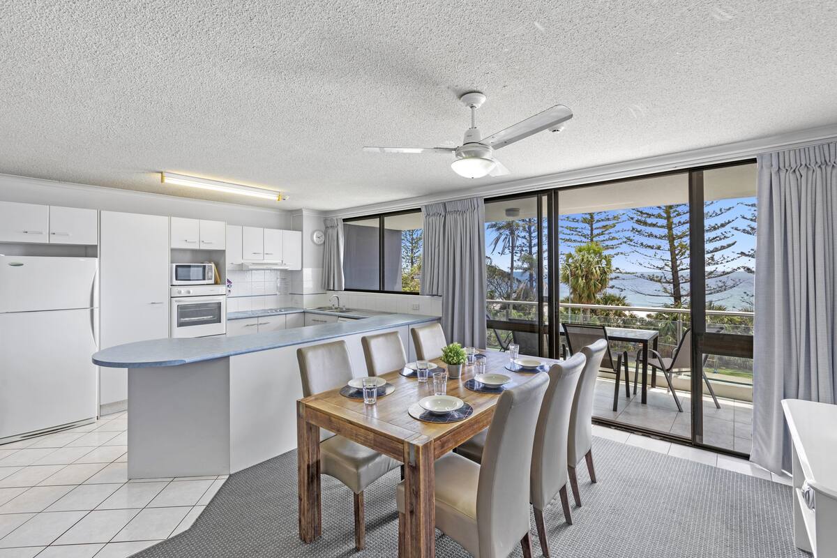 A modern kitchen with white cabinets, a built-in oven, and a large island with seating.