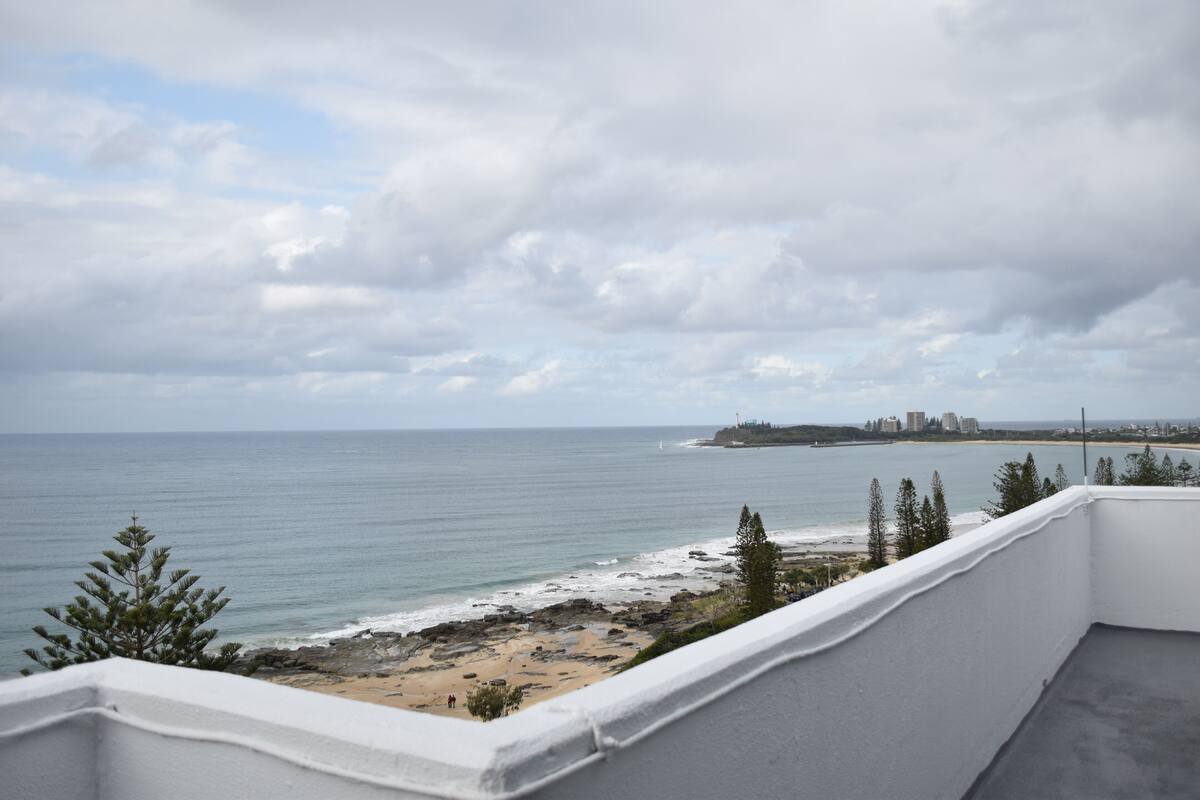 A balcony with a view of the beach and ocean.