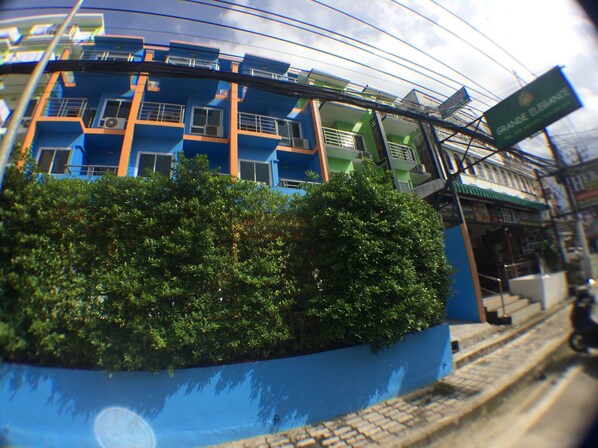 A modern building with a blue facade, a green signboard, and a visible staircase. - Grande Elegance Serviced Apartment (Patong)