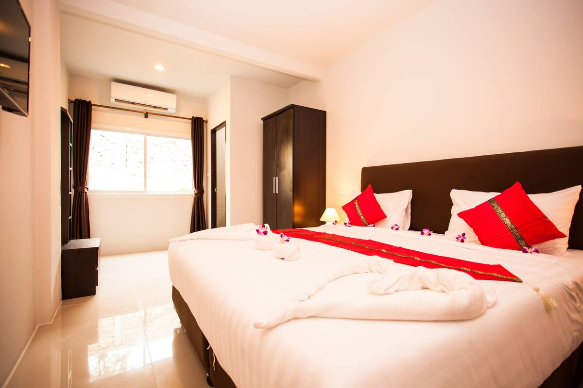 Hotelkamer met een groot bed, een kledingkast, een airconditioning en een raam met gordijnen.