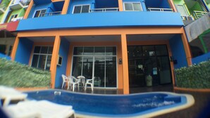 A multi-story hotel with balconies, a swimming pool, and outdoor seating. - Grande Elegance Serviced Apartment (Patong)