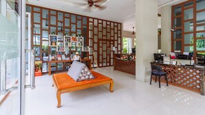 A spacious lobby with a reception desk, a seating area with a bench, and a large wooden partition with glass panels. - Siamaze Hostel (Bangkok)