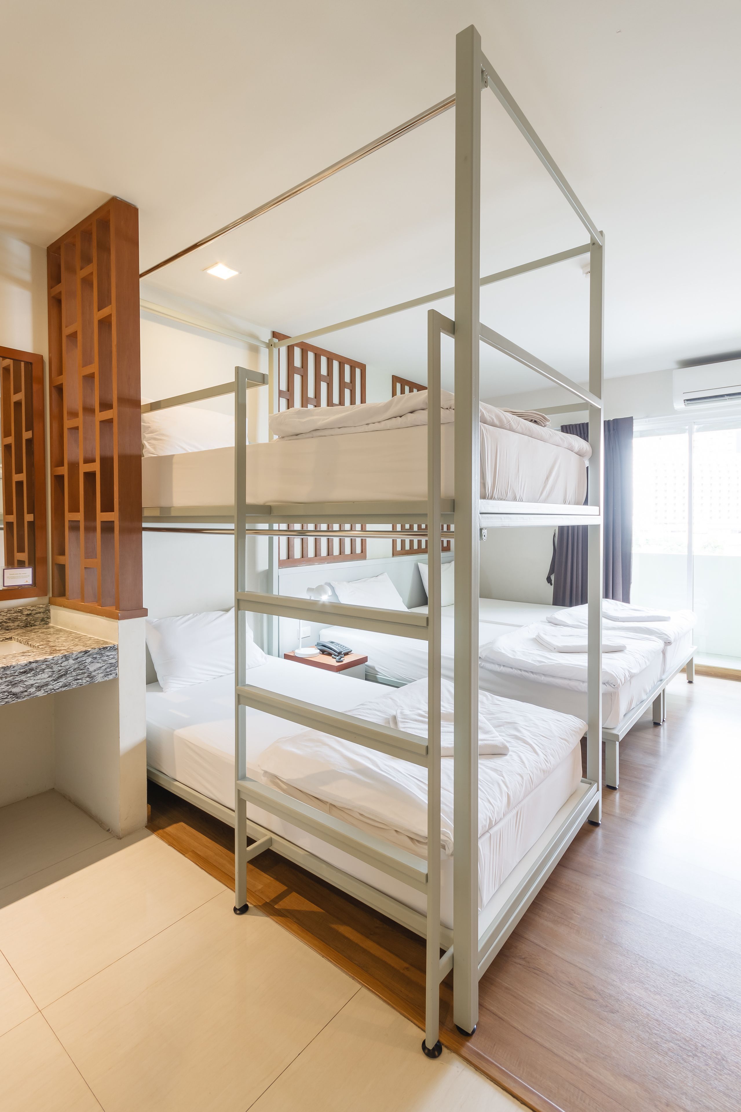 A bunk bed room with a wooden partition and a small desk area.