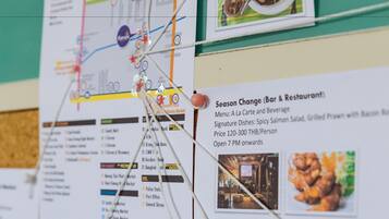 Un panel de información de viajes con varios mapas y menús de restaurantes sujetos a él.