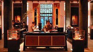 Un restaurante japonés tradicional con un mostrador central, pilares de madera y vitrinas decorativas.