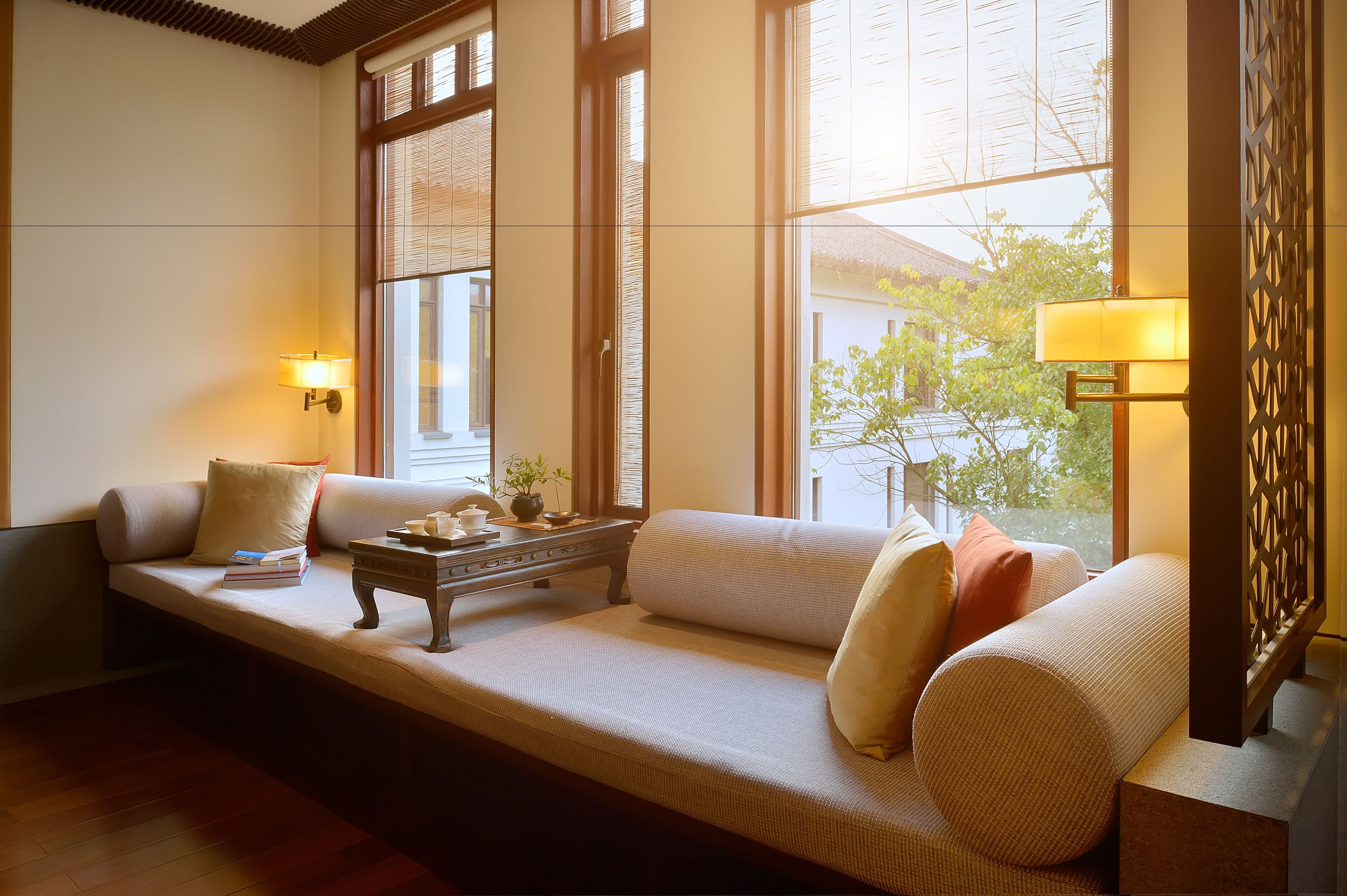A cozy seating area with a sofa, a small table, and two wall-mounted lamps.