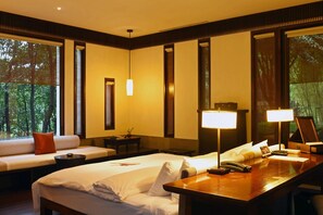 Une chambre d’hôtel avec un lit, un bureau, un canapé et de grandes fenêtres.