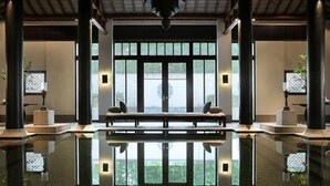 Un hall amplio con suelo reflectante, ventanas grandes y una zona de estar central.