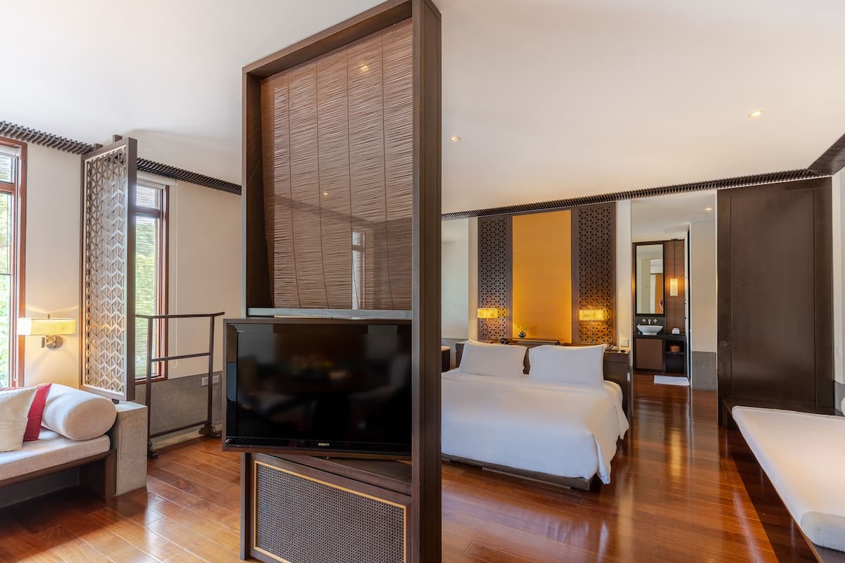Quarto de hotel moderno com uma grande televisão de tela plana, um sofá, duas camas e um closet espaçoso.