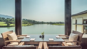 Una terraza con mesa y sillas que da a un lago, con un edificio al fondo.