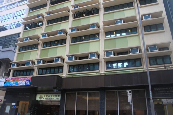 A multi-story hotel with balconies and air conditioning units. - Caritas Bianchi Lodge (Kowloon)