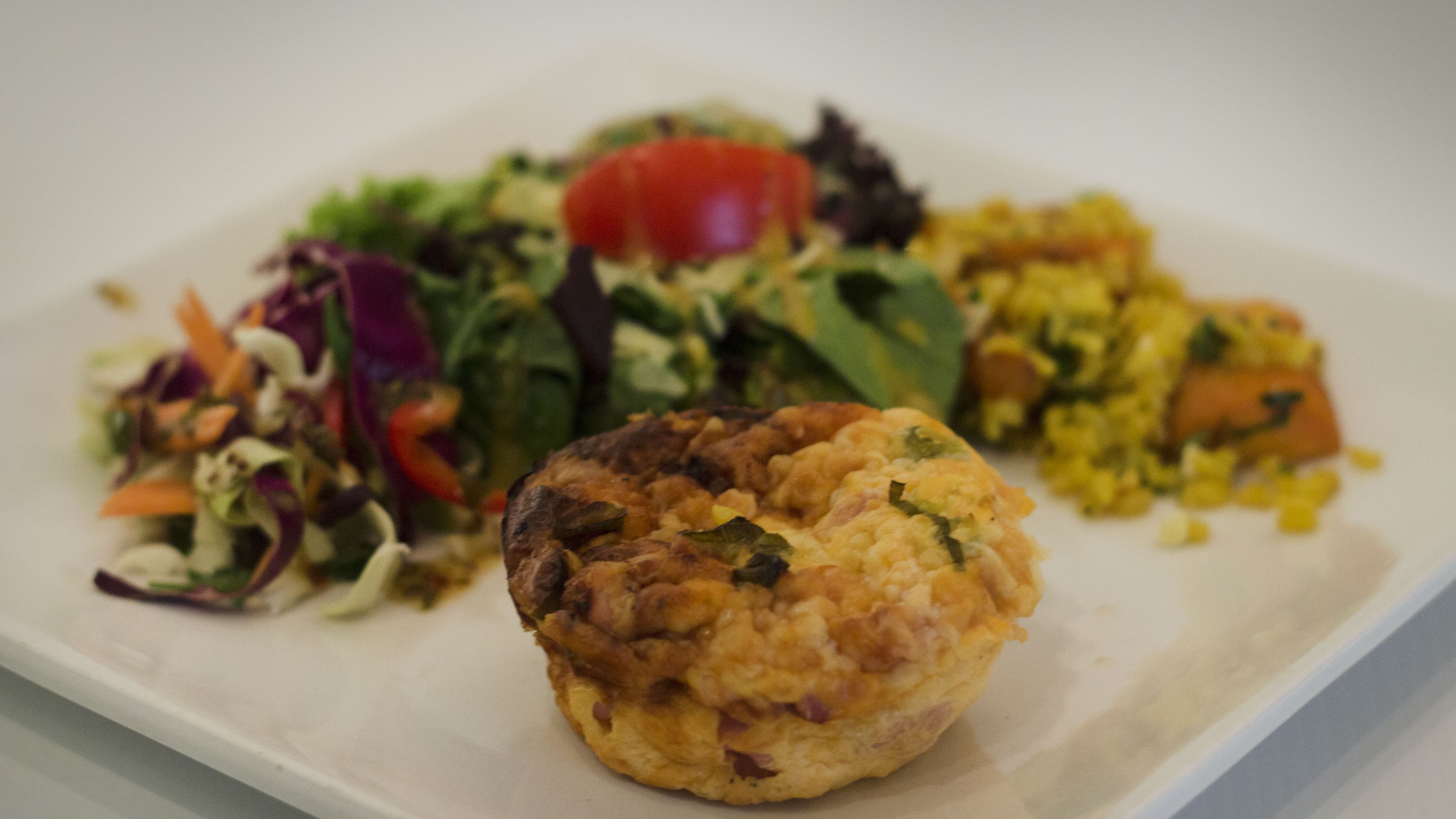 En tallerken med en muffin, en salat og en tilbehørsret.