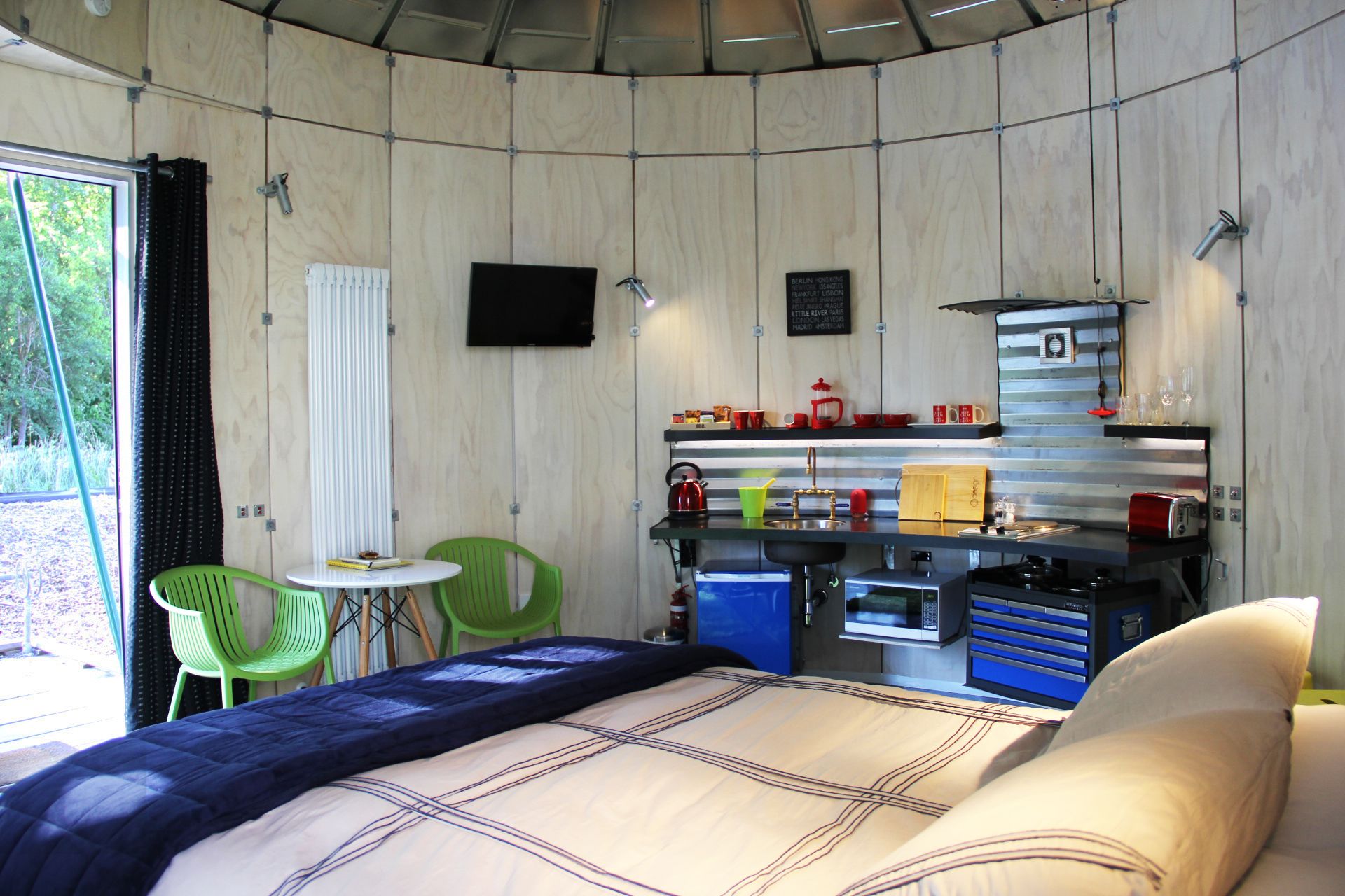 Habitació petita amb un llit, una taula i una cuineta.