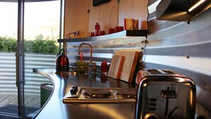Una cocina con encimera de acero inoxidable, hervidor, tostadora y estante de madera con utensilios de cocina.