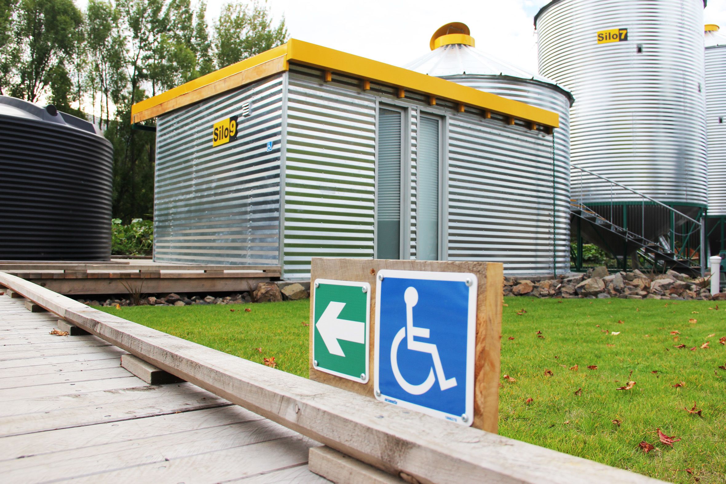 A building with a ramp leading to a door marked with a wheelchair accessibility sign.