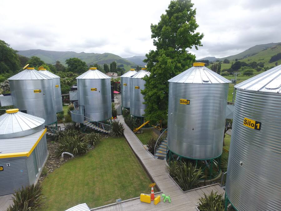 A series of large cylindrical silos in a rural setting with a grassy area and a staircase leading to the top.
