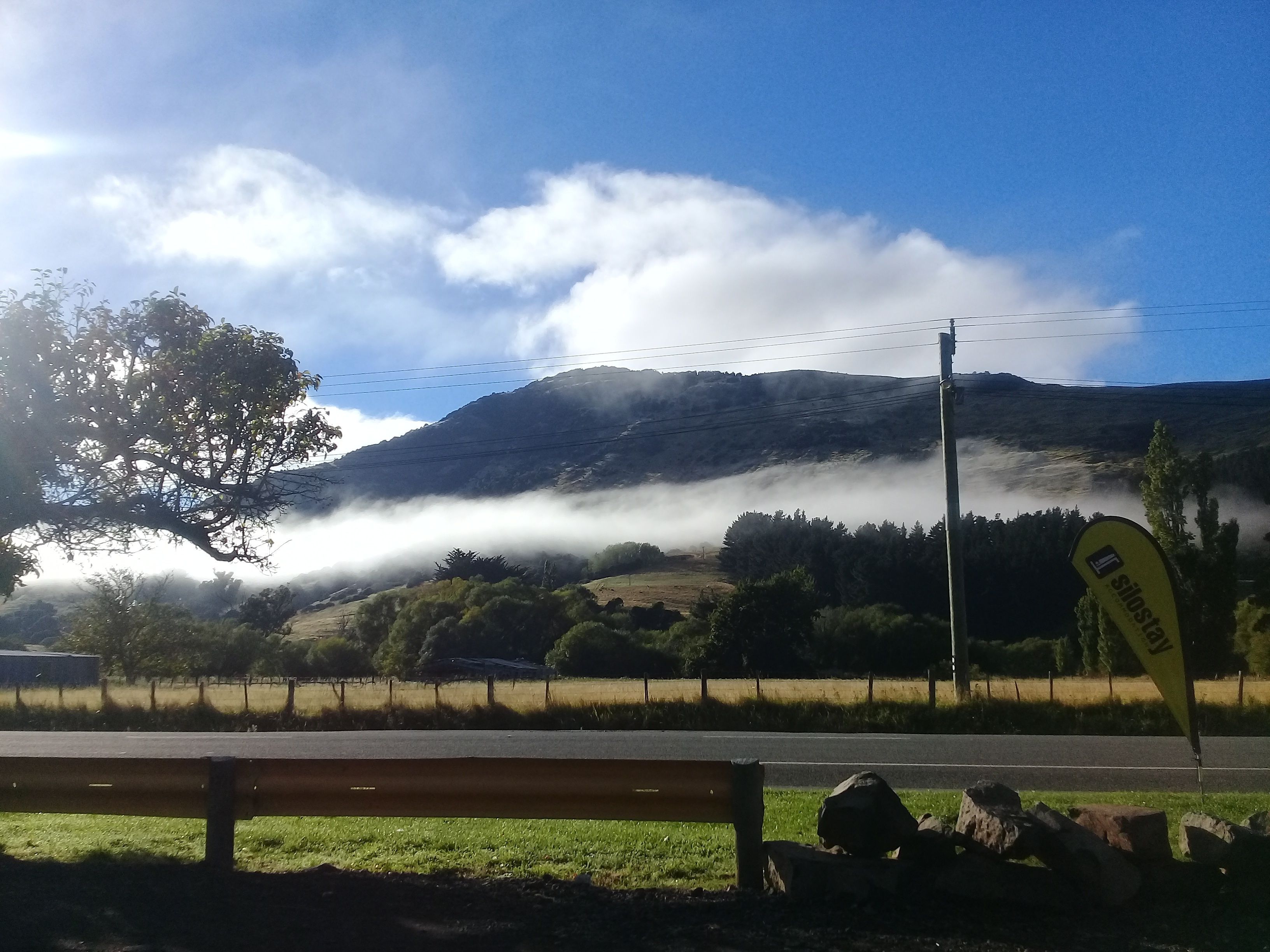 A bench, a road, a mountain, and a flag.