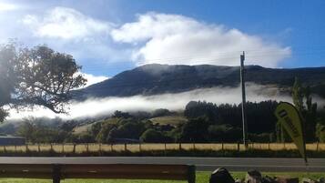 A bench, a road, a mountain, and a flag.