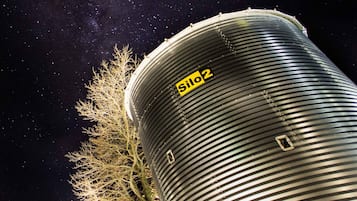 Grandes tanques cilíndricos con detalles estructurales visibles y un cielo nocturno estrellado al fondo.