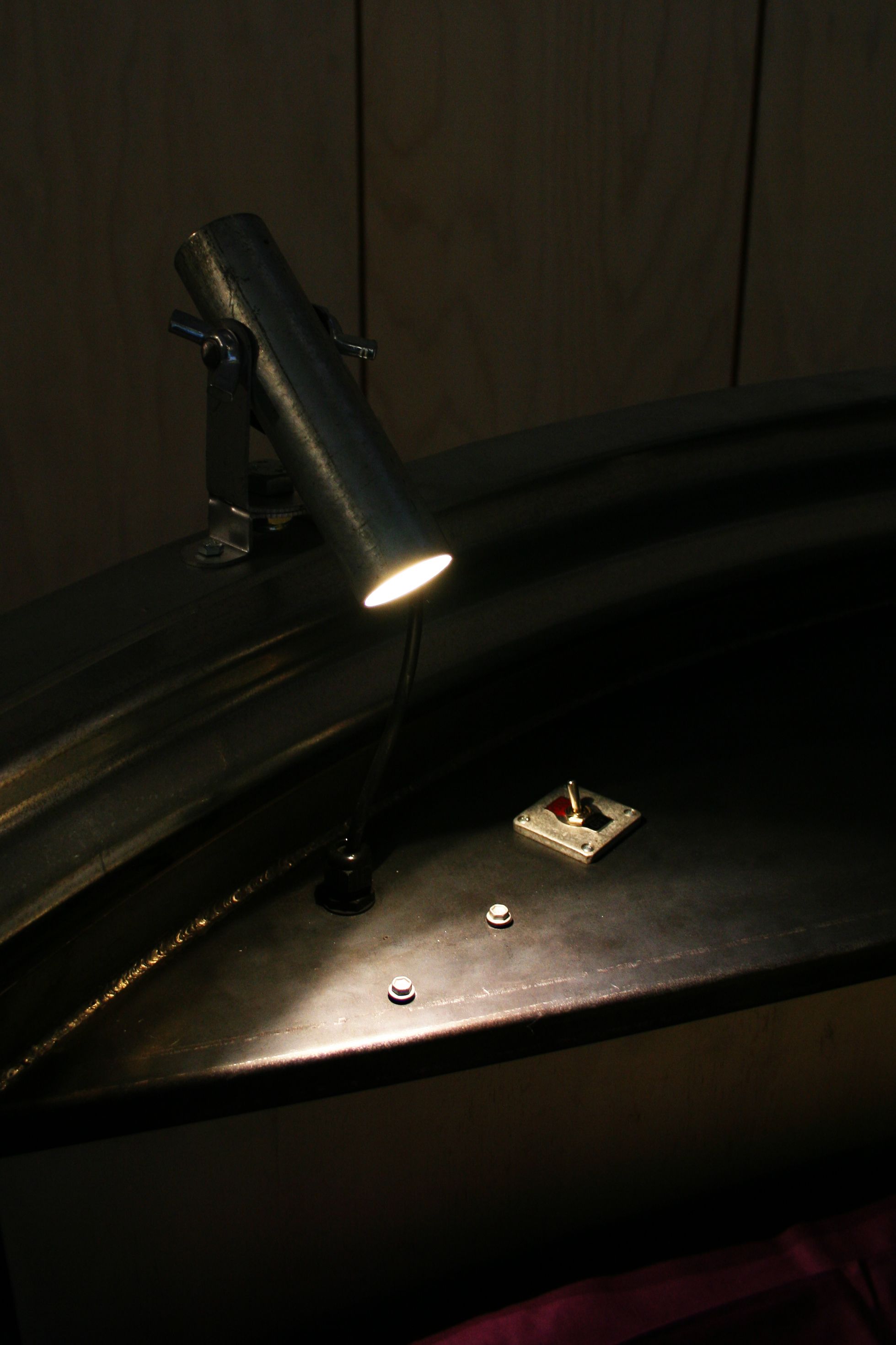 A close-up of a metallic surface with a light fixture and a small square object.