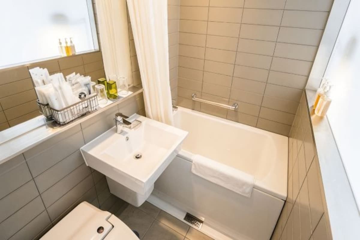 A bathroom with a sink, bathtub, and a window with curtains.