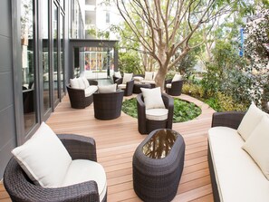 An outdoor seating area with wicker furniture and a central table, surrounded by greenery and a building facade. - Shinjuku Granbell Hotel (Tokyo)