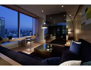 A modern living room with a city view, a dining area, and a cozy seating area. - Shinjuku Granbell Hotel (Tokyo)