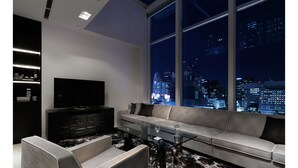 A modern living room with a large window, a flat-screen TV, a sofa, and a coffee table. - Shinjuku Granbell Hotel (Tokyo)