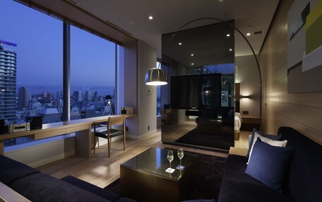 A modern living room with a large window, a sofa, a coffee table, and a TV.