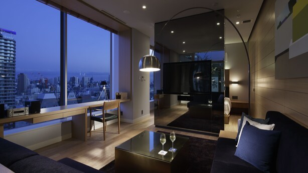 A modern living room with a large window, a sofa, a coffee table, and a TV. - Shinjuku Granbell Hotel (Tokyo)
