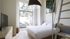 A modern bedroom with a bed, a TV, a ladder, and a large window. - Shinjuku Granbell Hotel (Tokyo)