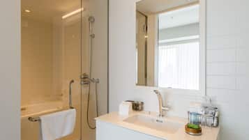 A modern bathroom with a glass-enclosed shower, a white sink, and a large mirror.
