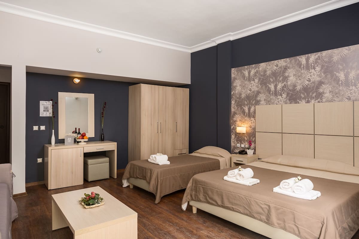 Une chambre d’hôtel avec deux lits, un bureau, une commode et un grand miroir.