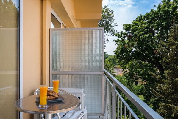 A balcony with a table, two glasses of orange juice, and a plate of cookies. - Arion Hotel Corfu (Corfu)