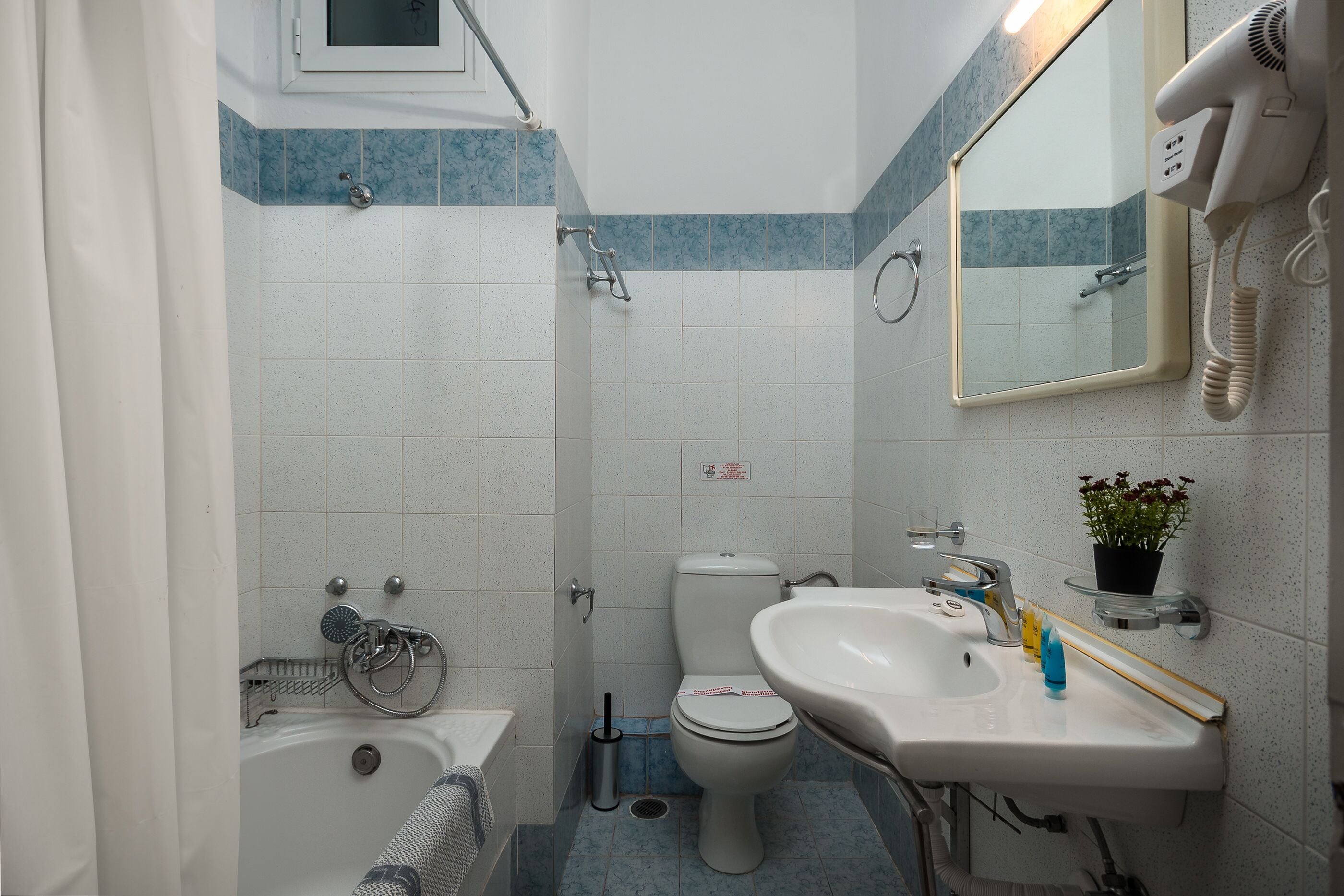 Ein Badezimmer mit Badewanne, Toilette, Waschbecken und einem an der Wand montierten Föhn.