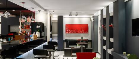 A modern bar area with a counter, seating, and a red decorative wall.