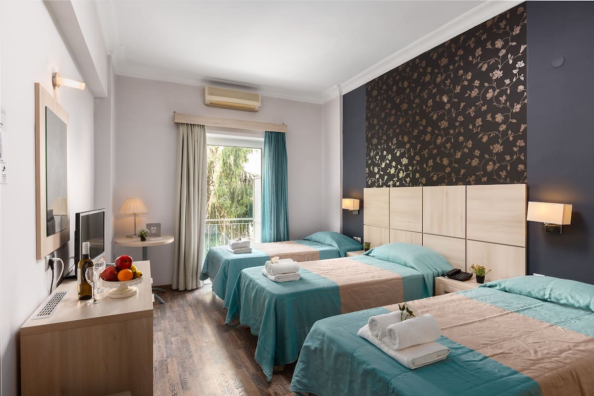 Une chambre d’hôtel avec deux lits, un bureau avec une lampe, une télévision et une fenêtre avec des rideaux.