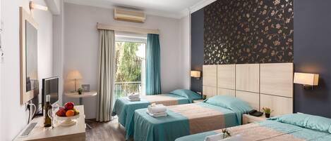 A hotel room with two beds, a desk with a lamp, a TV, and a window with curtains.