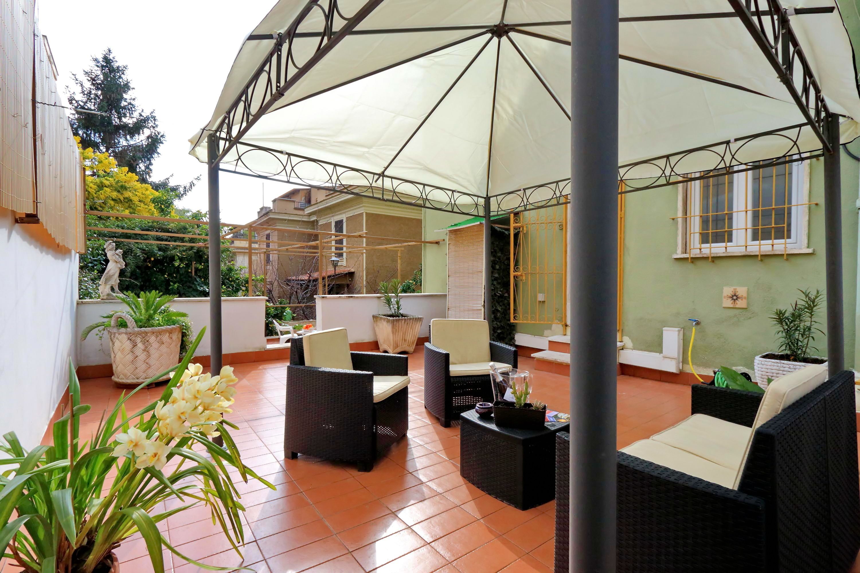 A covered outdoor seating area with wicker furniture and potted plants.