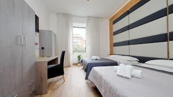 Hotellihuone, jossa on sänky, työpöytä, tuoli ja televisio.