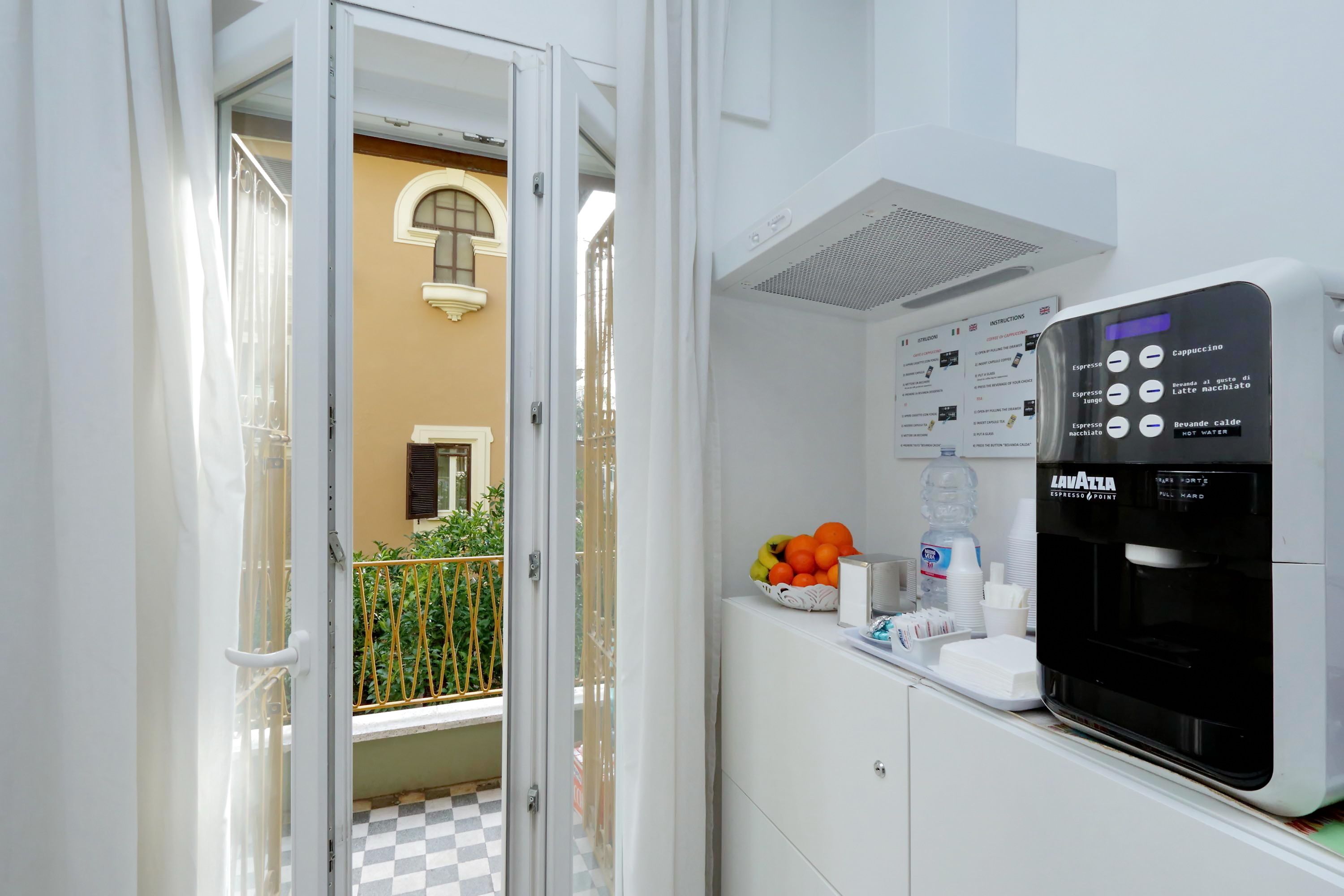 A compact kitchen with a coffee machine, a fruit bowl, and a water dispenser.