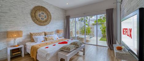 Un dormitorio moderno con una cama grande, un banco, un televisor y vistas al exterior.