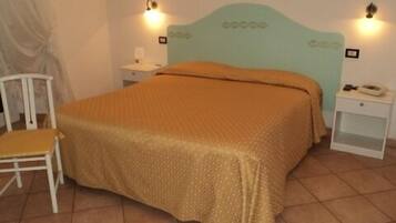 A bedroom with a bed, a chair, two bedside tables, and wall-mounted lights.