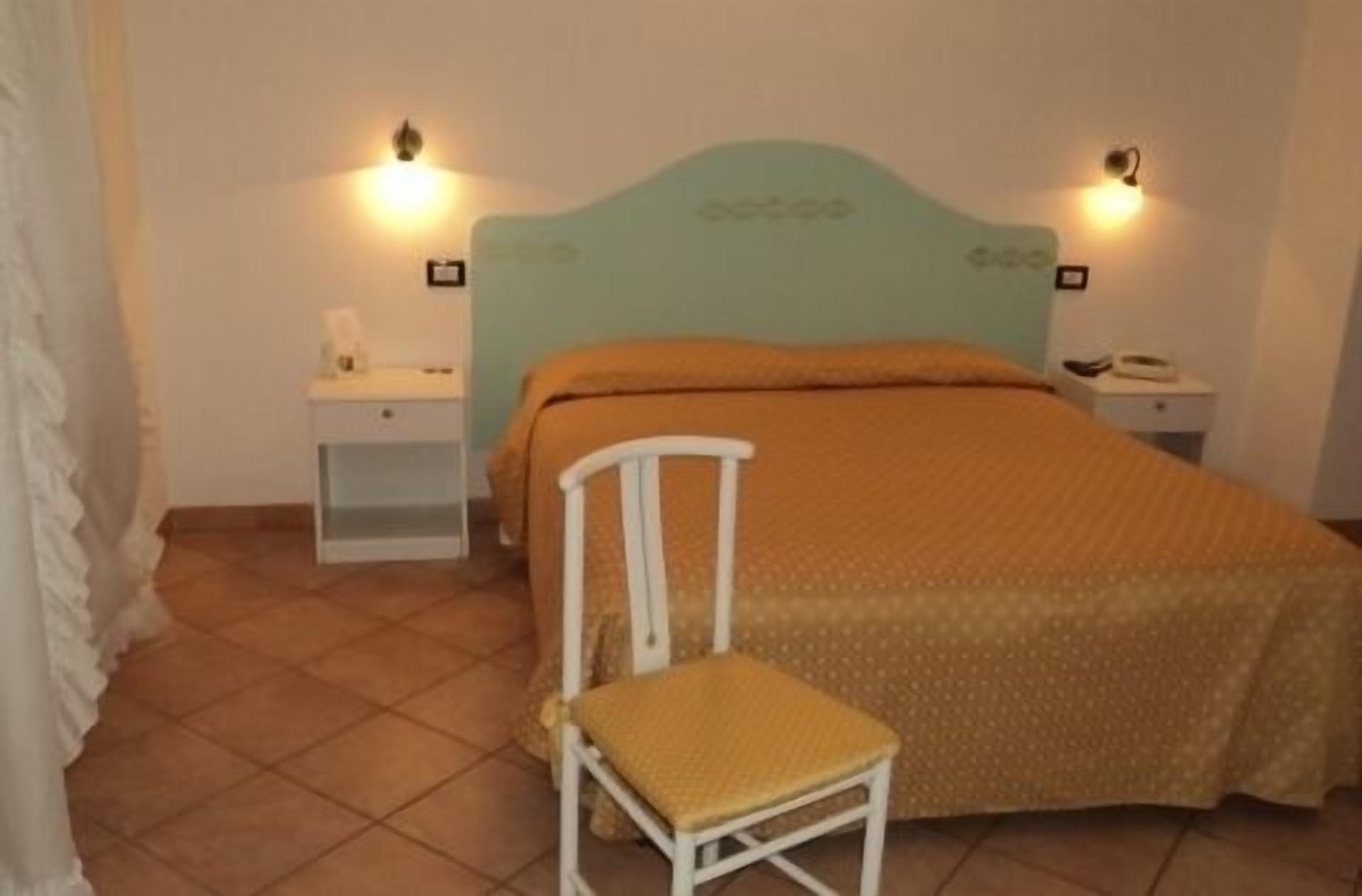 Una camera da letto con un letto, un comodino, una sedia e due lampade a parete.