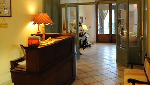 Una zona de recepción con un escritorio de madera, una lámpara y un árbol de Navidad.