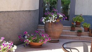 Un patio con plantas en macetas y una mesa de vidrio.