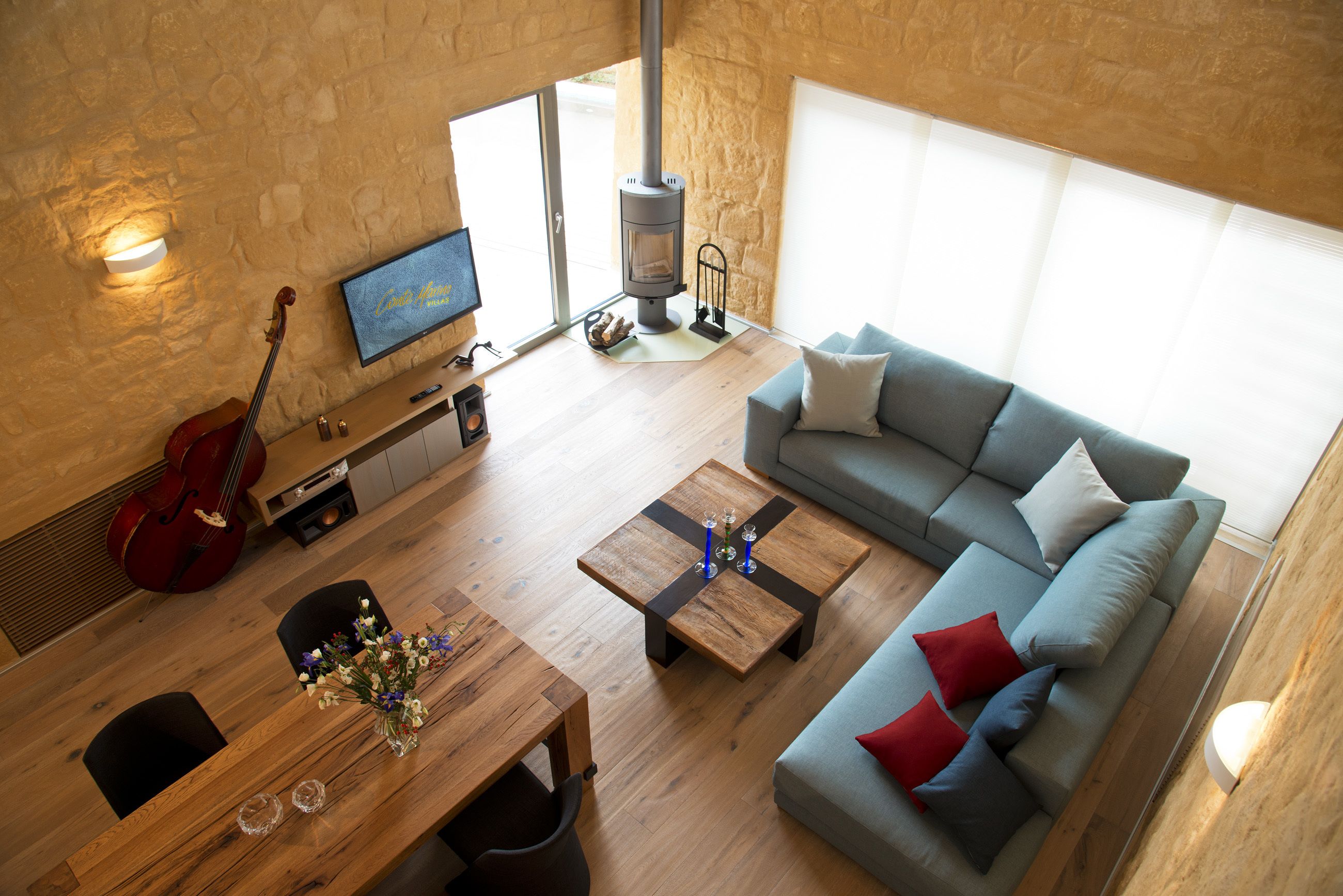 Ett modernt vardagsrum med en soffa, ett soffbord, en tv, en öppen spis och en röd gitarr.