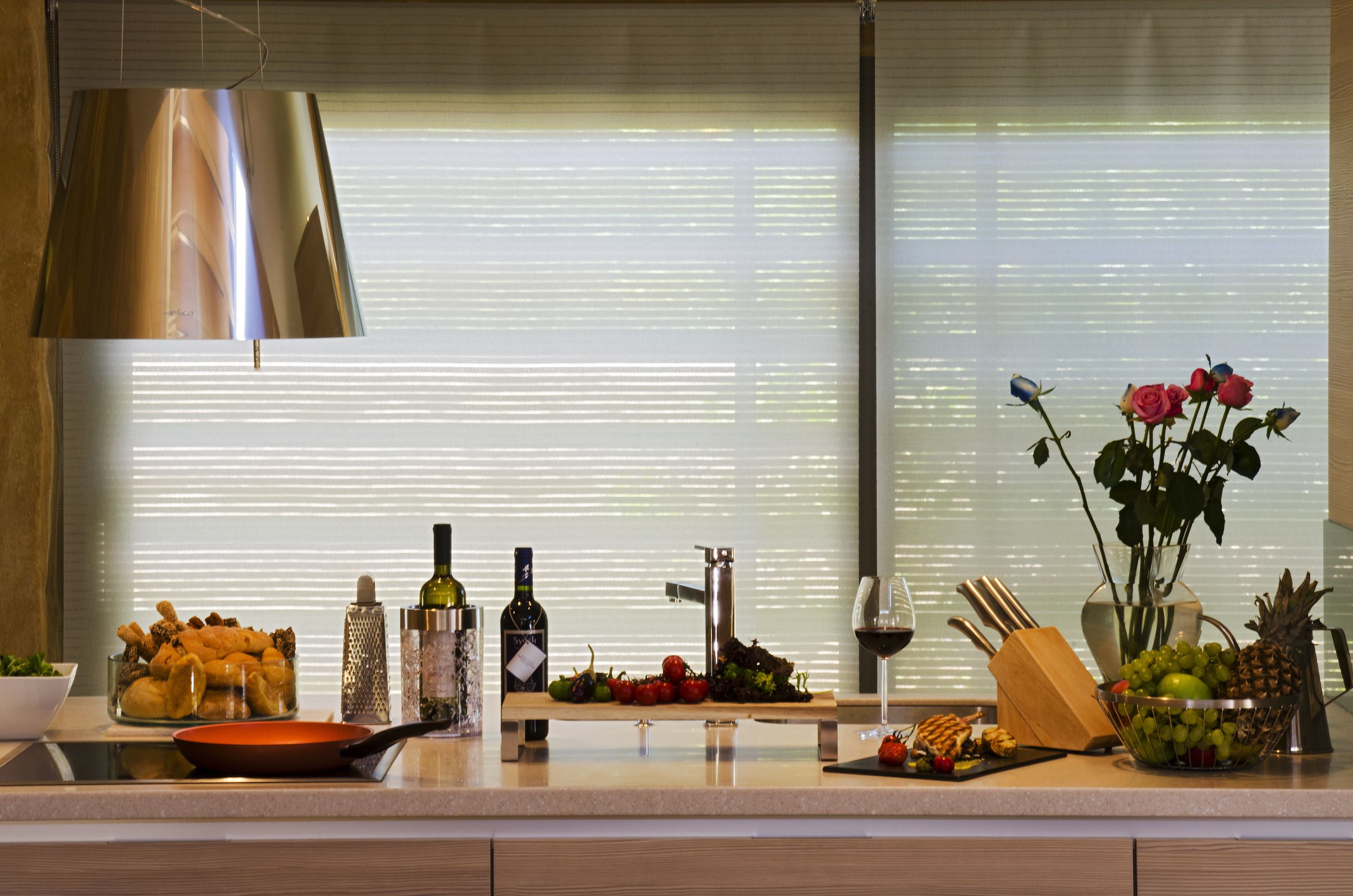 A kitchen counter with various food items, a wine bottle, and a fruit bowl.