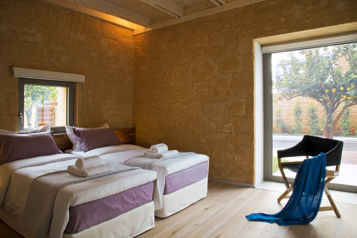 A room with two beds, a window, and a chair.